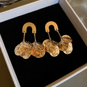 Detail of gold U-shaped earrings with hammered round sequins on a jewelry box