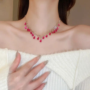 Close-up of a V-shaped necklace with red teardrop gems and diamonds on model