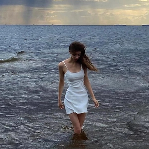 Short white bodycon camisole dress for women worn by a model in a scenic seaside setting