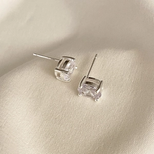 Detail view of silver oval zircon stud earrings on elegant cream satin fabric background