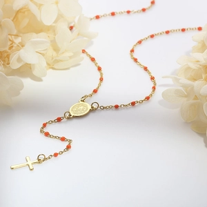 Macro detail of Bohemian rosary necklace with red resin beads and golden cross pendant