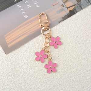 Close-up of pink flower keychain charms with gold-plated lobster clasp and enamel petals