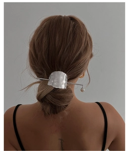 Detail of silver metal hairpin with pearl pendant on a model with golden earrings