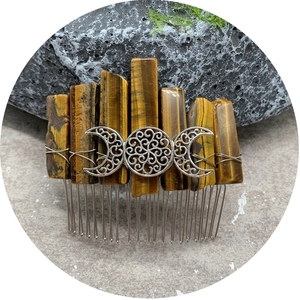 Tiger's eye crystal hair comb with silver triple moon filigree on stone surface
