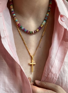 Close-up of 18k gold plated cross necklace layered with colorful natural stone beads
