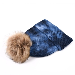 Détail du bonnet en tricot tie-dye avec pompon marron et texture côtelée chaude