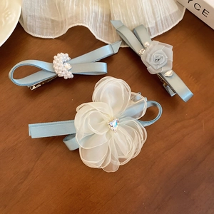 Detailed close-up of light blue mesh hair clips with pearls and fabric flowers on wood