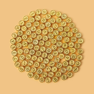 Golden acrylic letter beads for DIY jewelry making in a bulk pile on an orange background