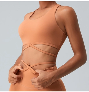 Detail view of terracotta yoga sports bra with criss-cross waist straps and high-waist leggings