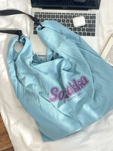 Sac fourre-tout bleu clair à texture gaufrée avec texte violet sur un fond minimaliste