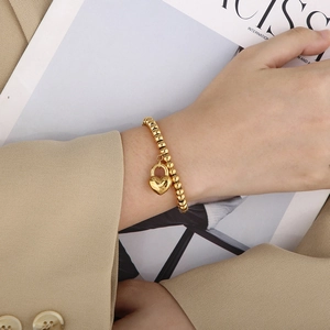 Detail of 18K gold plated bead chain bracelet with a heart shaped lock pendant charm