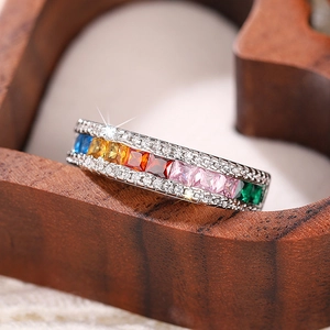 Macro detail of silver rainbow zircon ring with square cut gems on a heart wooden base