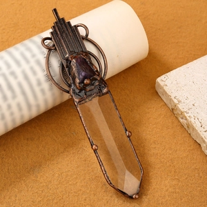 Retro bronze pendant with clear white crystal prism and amethyst raw stone on textured background