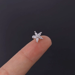 Macro detail of tiny daisy stud earring with marquise cut zircon on fingertip