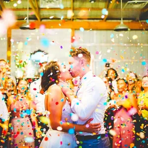 Dynamic view of colorful round paper confetti scattering over a wedding couple and guests