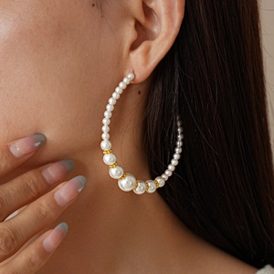 Elegant C-shaped pearl hoop earrings with golden spacers shown on a female model