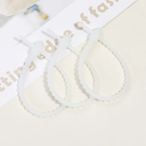 Close-up of three white adjustable silicone cable ties with notched scale design