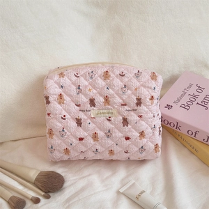 Detailed view of quilted pink pouch featuring a cute bear print and secure zipper top