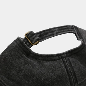 Detail of the adjustable brass metal buckle and washed denim texture on baseball cap