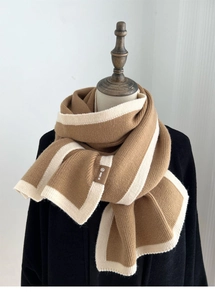 Close-up of thick camel knit scarf with off-white trim and small brand label