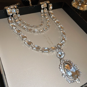 Macro detail of layered necklace featuring rectangle stones and a pear-shaped waterdrop pendant