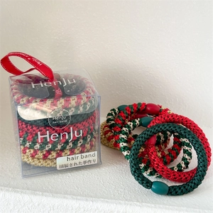Detail of red and green woven elastic hair bands in a transparent gift box with red ribbon