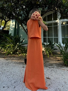 Rear view of bright orange linen two-piece set with maxi skirt and sleeveless top