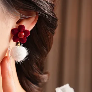 Elegant velvet flower earrings with white pom-poms and pearls on model for winter fashion