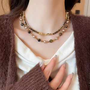 Close-up of double-layer necklace with tiger eye stones and pearls worn on neck