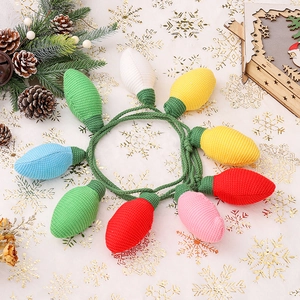 Colorful crochet Christmas bulb ornaments set on a festive white tablecloth with pine cones
