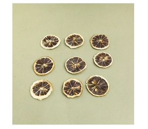 Detailed top view of nine dried lemon slices for DIY Christmas crafts on light green background