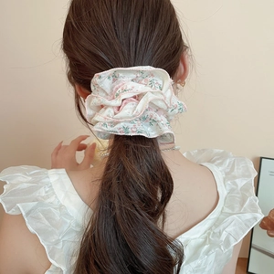 Detailed view of floral fabric scrunchie with lace trim worn on a ponytail