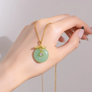 Elegant gold titanium steel necklace with a green jade-like pendant held by hand