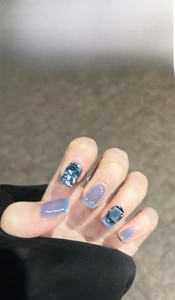 Vue détaillée du vernis à ongles bleu glacé avec des décorations de pierres fines.