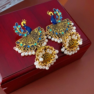 Close-up of vintage golden peacock earrings with blue enamel and pearl tassels