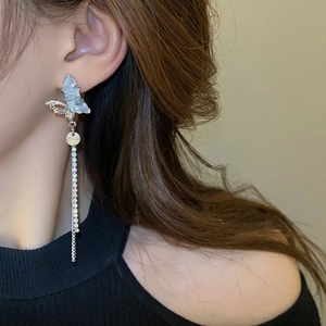 Vue détaillée des boucles d'oreilles papillon argentées à pompons sur un mannequin