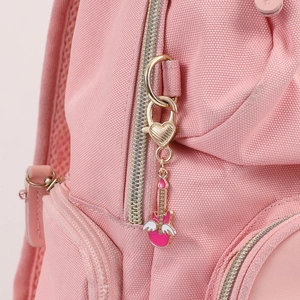Close-up of pink backpack fabric with guitar pendant and gold heart-shaped metal clasp