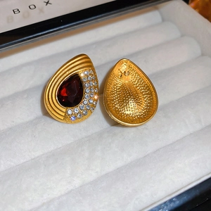 Detailed view of teardrop earrings with red pear-cut gemstone and crystal halo