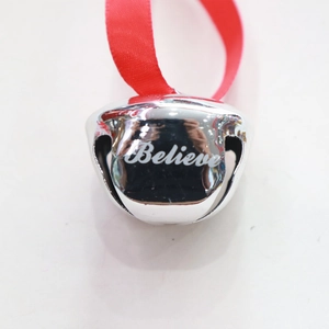 Close-up of a silver metal bell with red ribbon and white 'Believe' engraving for Christmas
