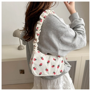 Detail of white corduroy underarm bag with strawberry print shown on model for size reference