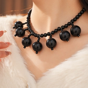 Detail of elegant black acrylic beaded necklace with tassel drop on a female model