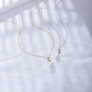 Detail of gold and silver pearl necklaces with cubic zirconia accents on white fabric