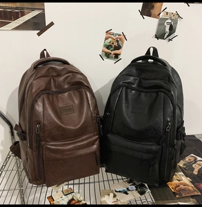 Dettaglio degli zaini in pelle PU nero e marrone scuro su un espositore in metallo