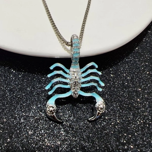 Detail view of a silver scorpion pendant with blue accents and glowing effect on a base