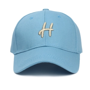 Détail d'une casquette de baseball bleu clair avec broderie 3D de la lettre H en relief