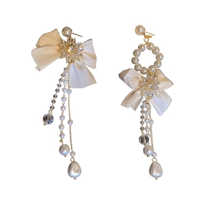 Elegant asymmetrical bow earrings with imitation pearls and crystal fringe on white background