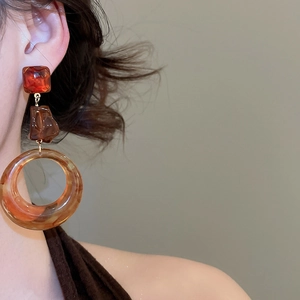 Dettaglio di orecchini vintage in resina ambra su modella per un look di tendenza