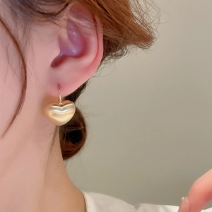 Elegant gold plated heart shaped drop earring worn by model for a minimalist style