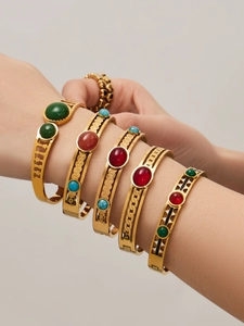 Detail of stacked gold-plated stainless steel bangles with red agate and turquoise stones