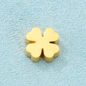Vue macro du pendentif trèfle doré 3D à effet miroir sur fond texturé bleu clair